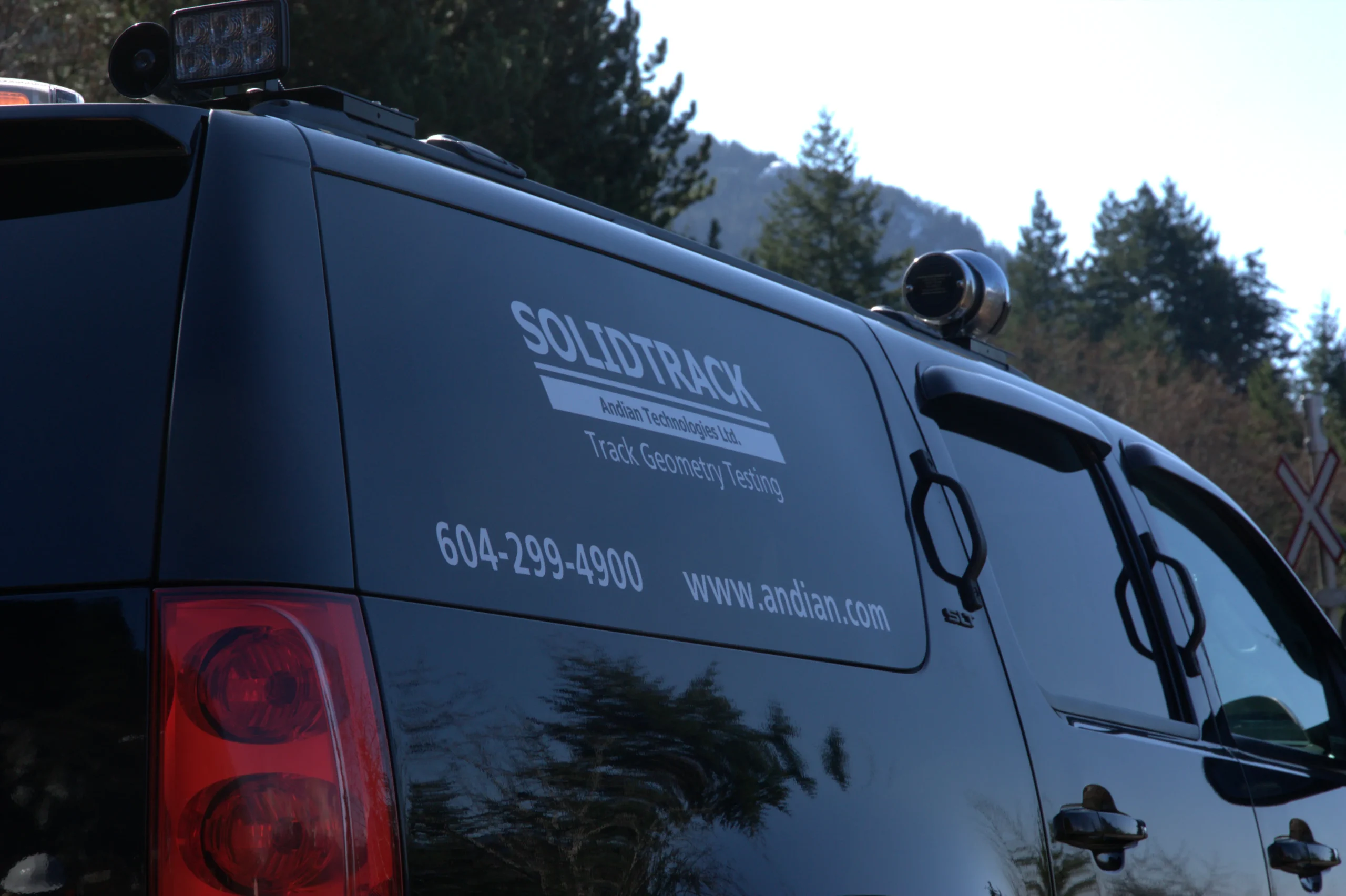 Image of SolidTrack logo and contact information located on the back right window of a company vehicle.